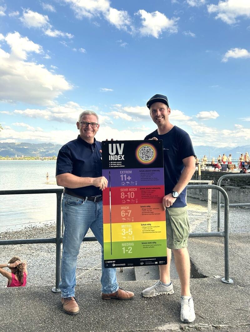 Thomas Kaleja, Gesch&auml;ftsstellenleiter der Gesundheitsregionplus Landkreis Lindau (links im Bild) und Josef Friesacher, Lindi Bodensee GbR (rechts im Bild) bei der &Uuml;bergabe der UV-Index-Tafel im &raquo;Lindi&laquo; 