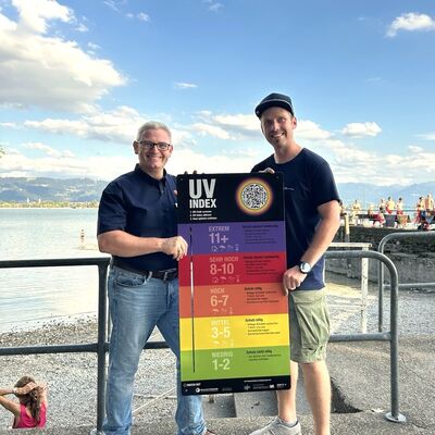 Thomas Kaleja, Geschäftsstellenleiter der Gesundheitsregionplus Landkreis Lindau (links im Bild) und Josef Friesacher, Lindi Bodensee GbR (rechts im Bild) bei der Übergabe der UV-Index-Tafel im »Lindi« 